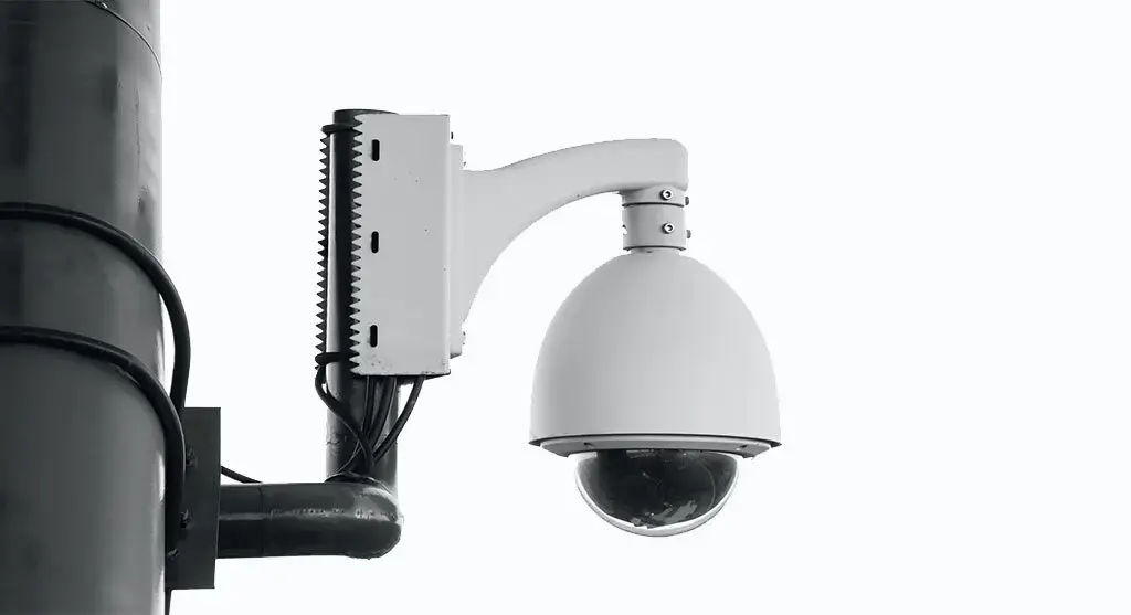 Wall-mounted dome security camera with a protective casing.